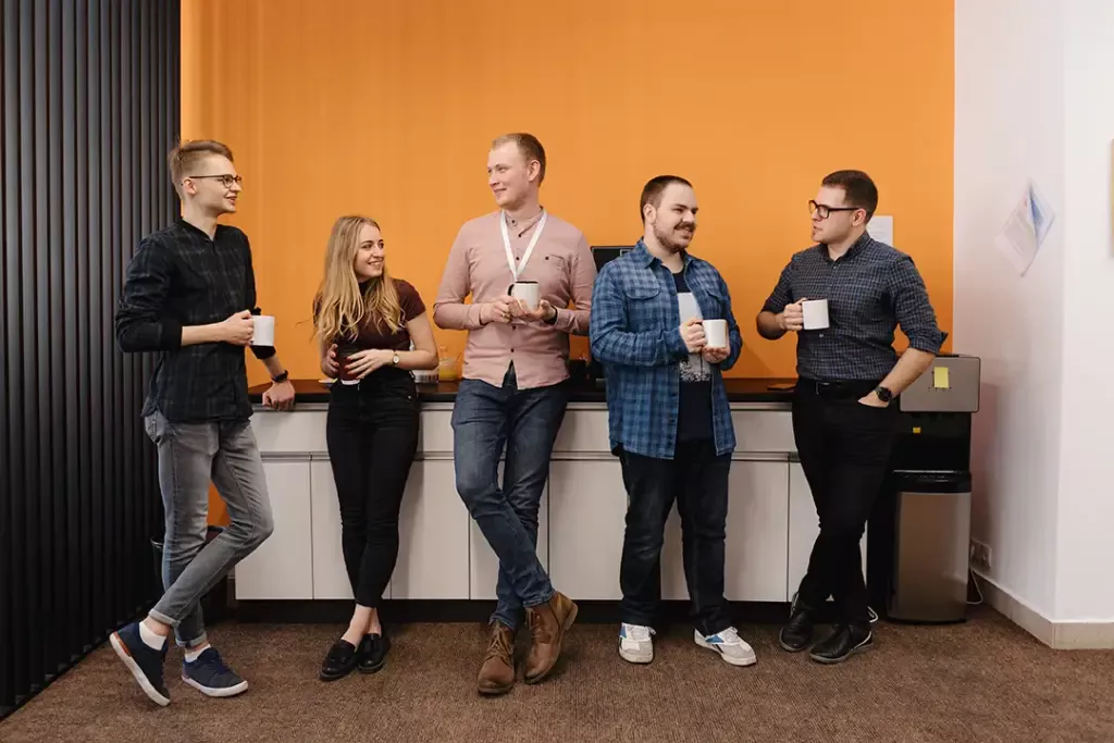 a group of people standing in a room with white cabinets and white countertops